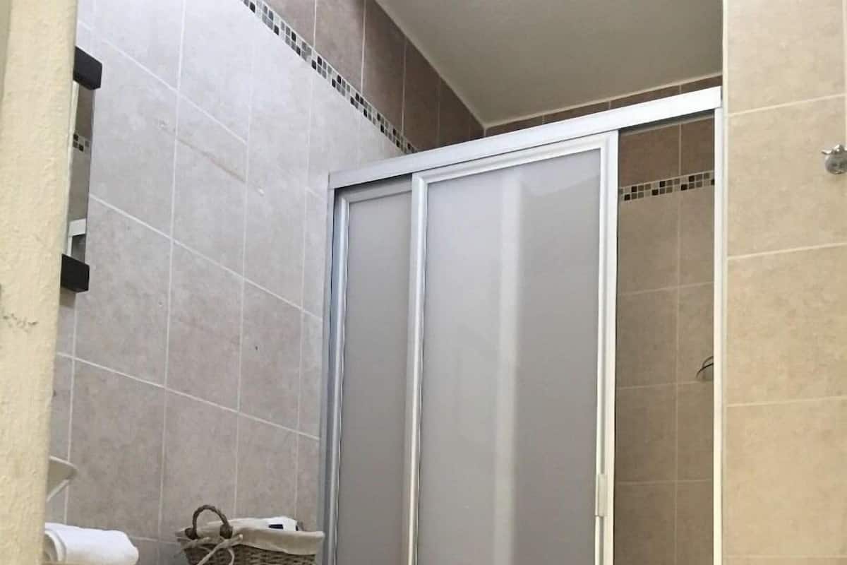 A bathroom with a toilet, a shower enclosure, and a wooden vanity.