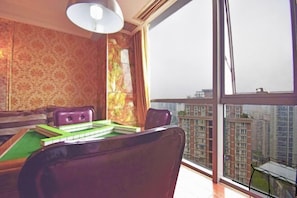 Una habitación con mesa de billar, una silla y vistas a edificios altos a través de amplias ventanas.