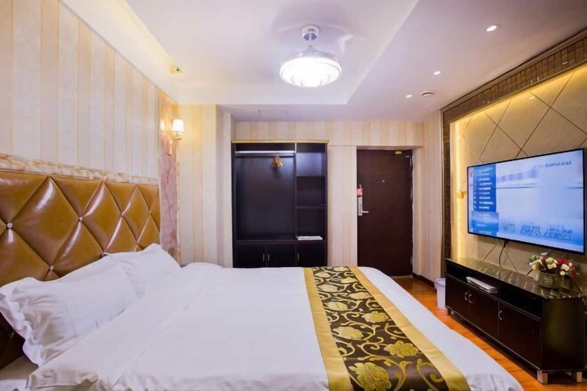 A hotel room with a large bed, a television, a wardrobe, and a ceiling light.