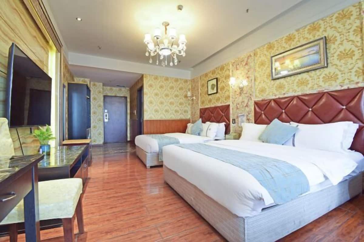A hotel room with a large bed, a desk with a chair, and a television.