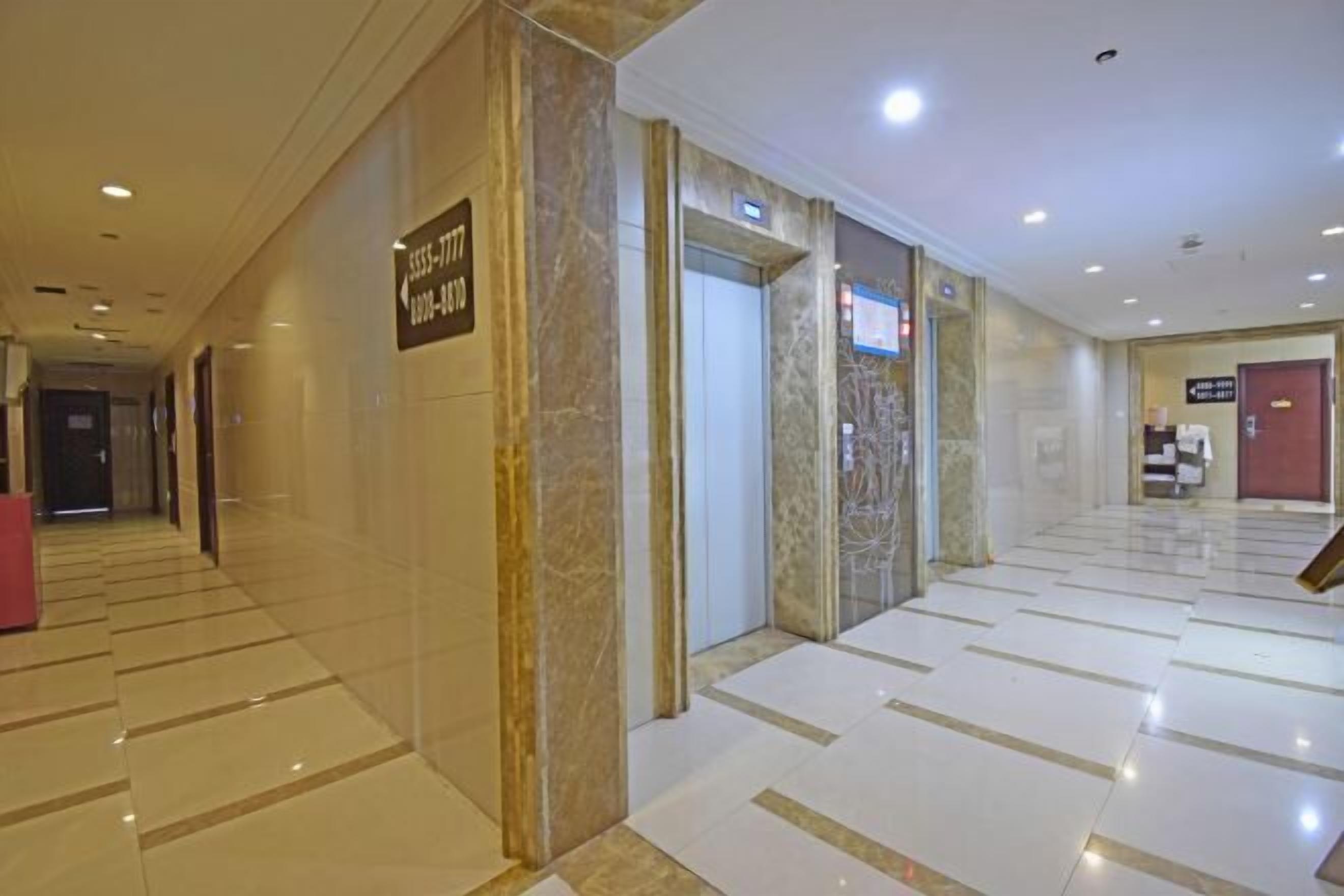 A hotel lobby with a marble floor, a reception desk, and an elevator.