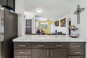 Una cocina moderna con encimera de mármol, armarios oscuros y ventilador de techo.