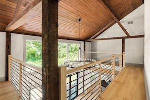 Ein geräumiges Zimmer mit Holzboden und einem Balkon mit Metallgeländer.