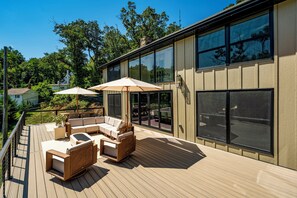 Eine Terrasse mit Gartenmöbeln und einem großen Fenster mit Blick auf eine Wohngegend.