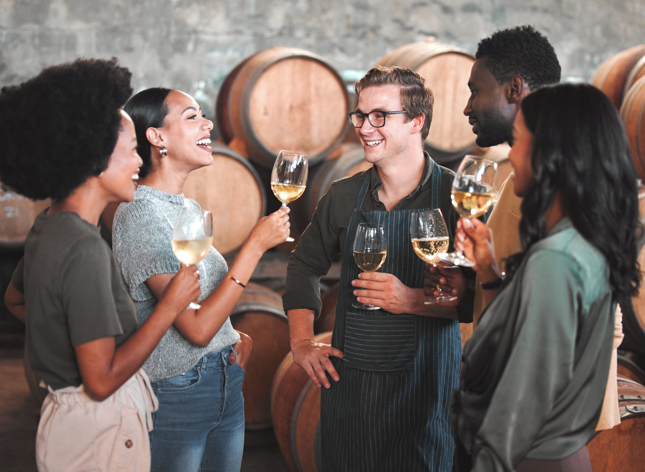 A group of people in a wine cellar holding wine glasses.