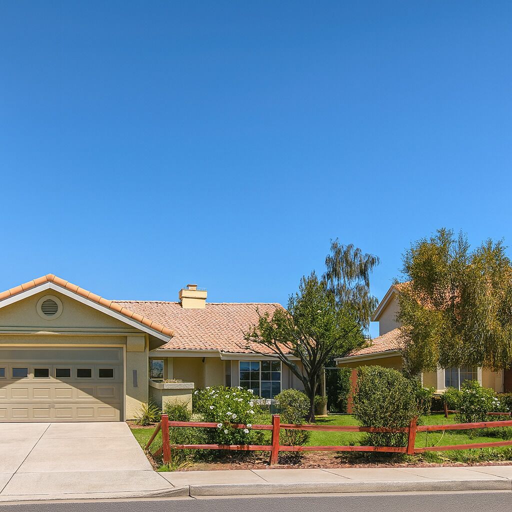 A two-story house with a garage, a red fence, and a well-maintained lawn.