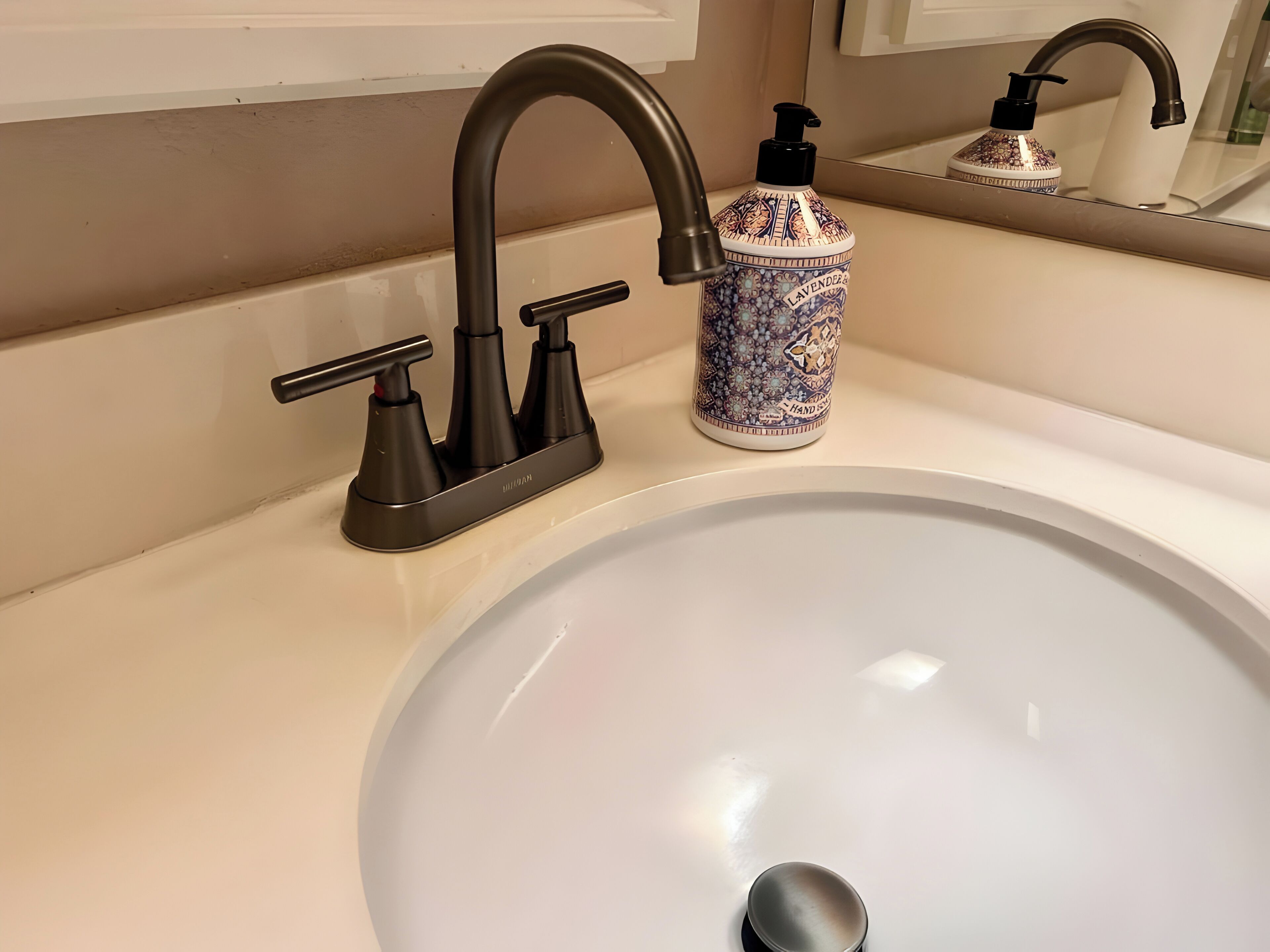 Un lavabo de bany amb un aixeta moderna i un dispensador de sabó decoratiu.