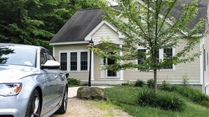 Una casa con vialetto, un'auto parcheggiata e un albero nel giardino.