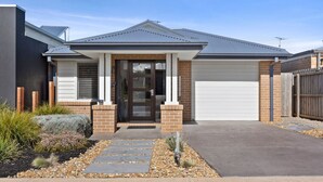 A modern two-story house with a garage, a front porch, and a well-maintained garden.