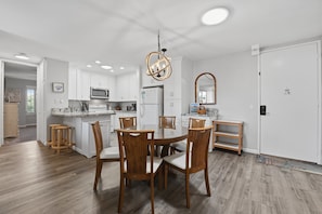 Une cuisine moderne avec des meubles blancs, un îlot central et des chaises en bois.