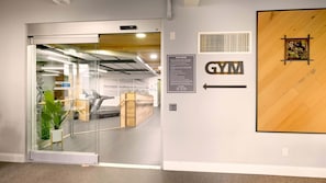 A gym entrance with a treadmill, a sign indicating gym rules, and a directional arrow.
