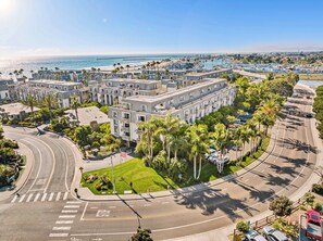 Een meerlaags hotel met een centrale binnenplaats, omringd door palmbomen en uitzicht op het strand.