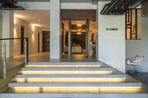 Step into a stylish lobby with a central staircase and minimalist design, featuring a mix of glass and wood elements.