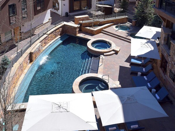 A rooftop pool area with multiple hot tubs and lounge chairs.