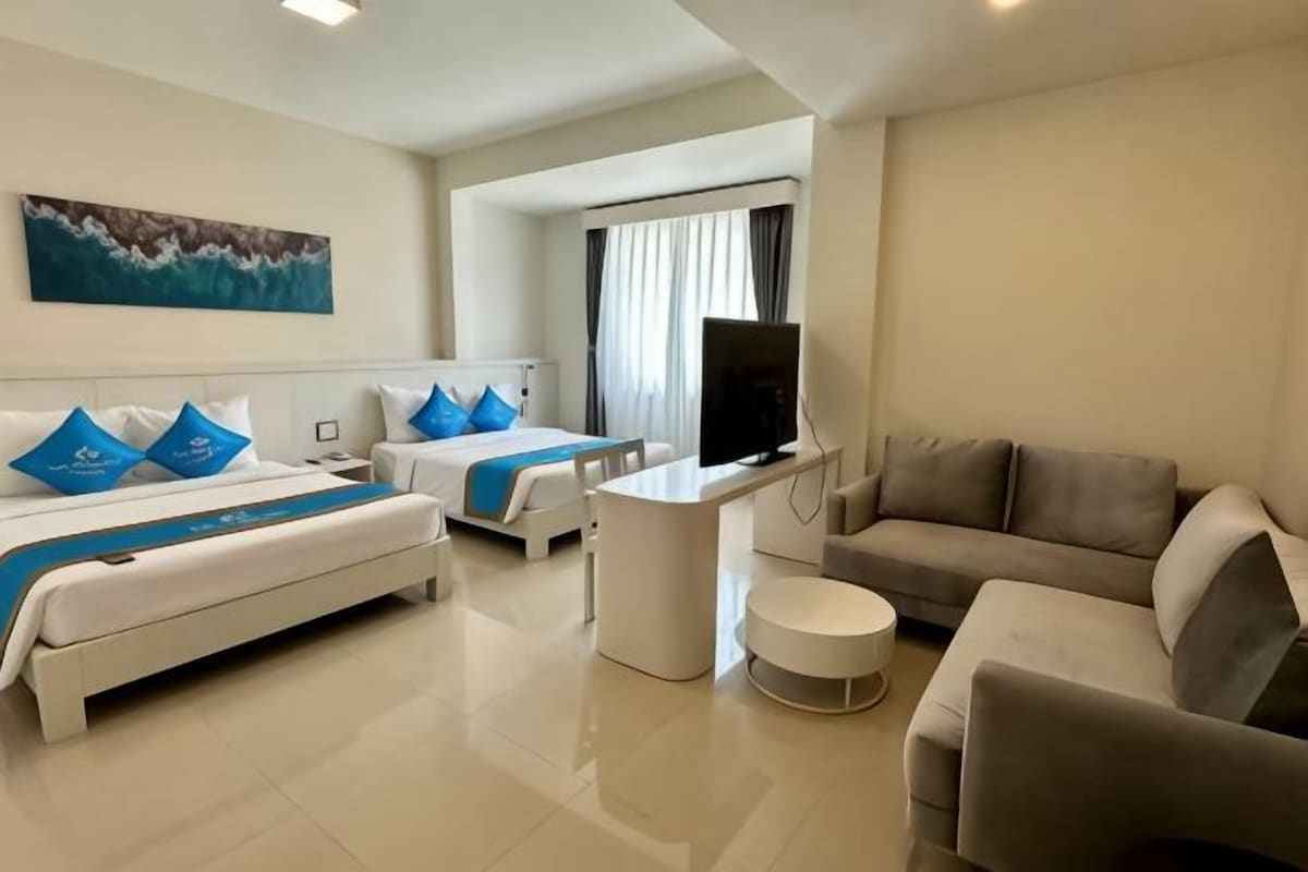 Habitación de hotel con dos camas, un sofá, un televisor y un escritorio.