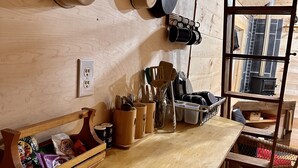 Une cuisine en bois avec des ustensiles de cuisine suspendus, un comptoir en bois et une fenêtre donnant sur un immeuble.