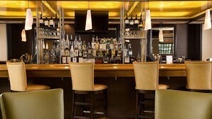 Eine Bar mit mehreren Barhocker und einer Theke, an der Flaschen stehen.