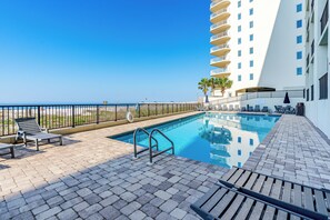 A rooftop pool with lounge chairs and a view of the ocean.
