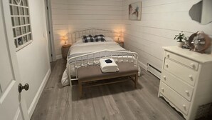 Una camera da letto con un letto, lampade ai comodini, una cassettiera e una finestra.