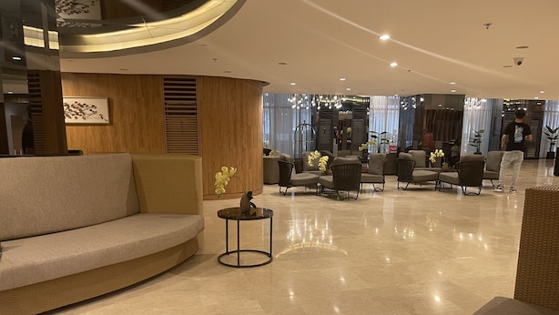 Un hall d’entrée moderne avec un canapé incurvé, des meubles en osier et une petite table sur laquelle est posé un vase de fleurs.