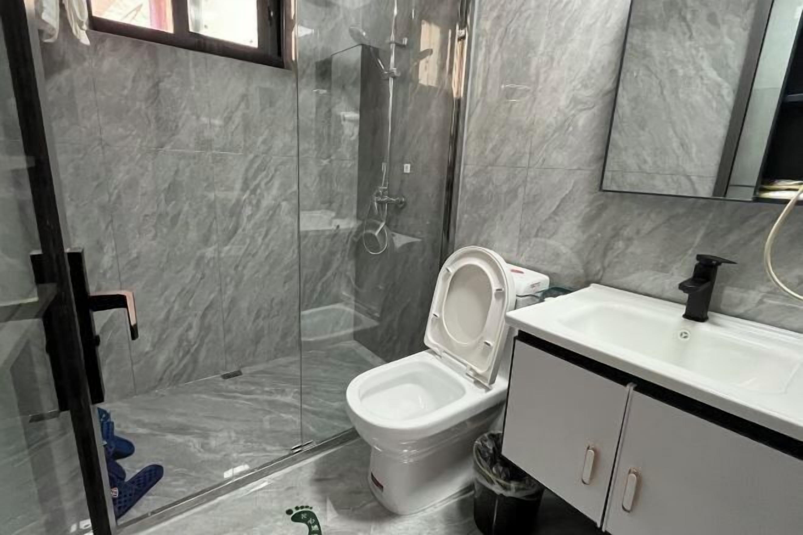 A bathroom with a glass-enclosed shower, a white toilet, and a sink with a black faucet.