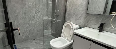 A bathroom with a glass-enclosed shower, a white toilet, and a sink with a black faucet.
