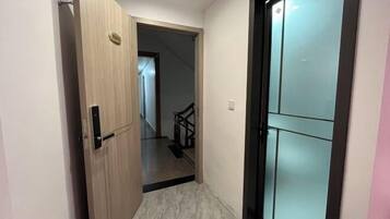 Un pasillo con una puerta de madera y otra de cristal que da a una escalera.
