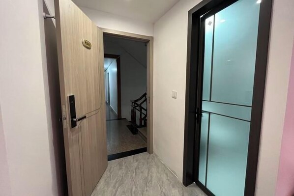 A hallway with a wooden door and a glass door leading to a staircase. - House 67, Yandang Mountain (Yueqing)