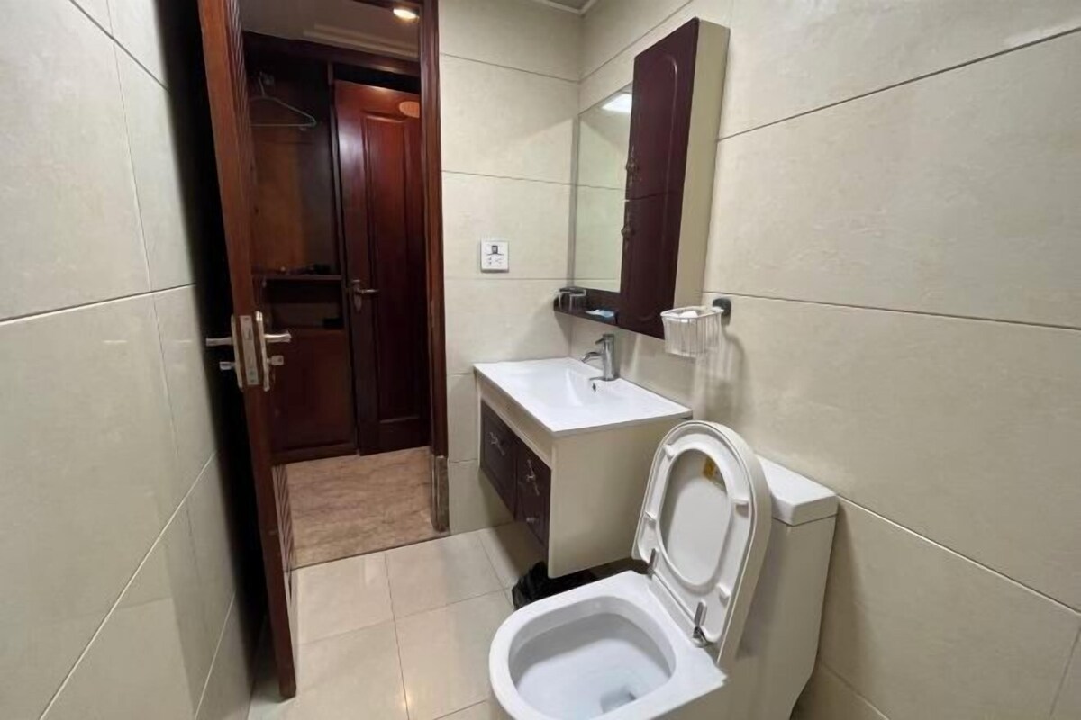 A compact bathroom with a toilet, sink, and a wooden door leading to a closet.