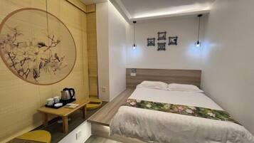 Habitación de hotel pequeña con cama, mesita de noche y una obra de arte colgada en la pared.