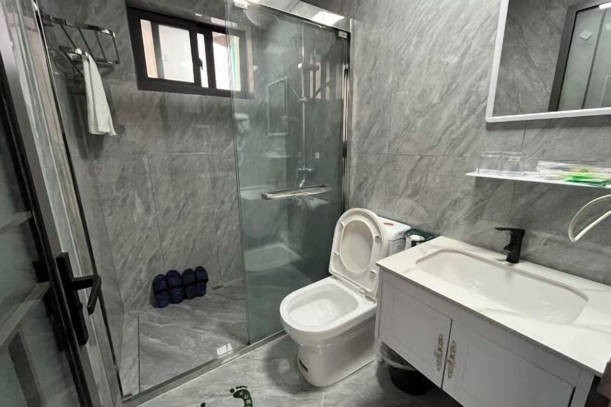 A modern bathroom with a glass-enclosed shower, a white toilet, and a white sink with a mirror above.