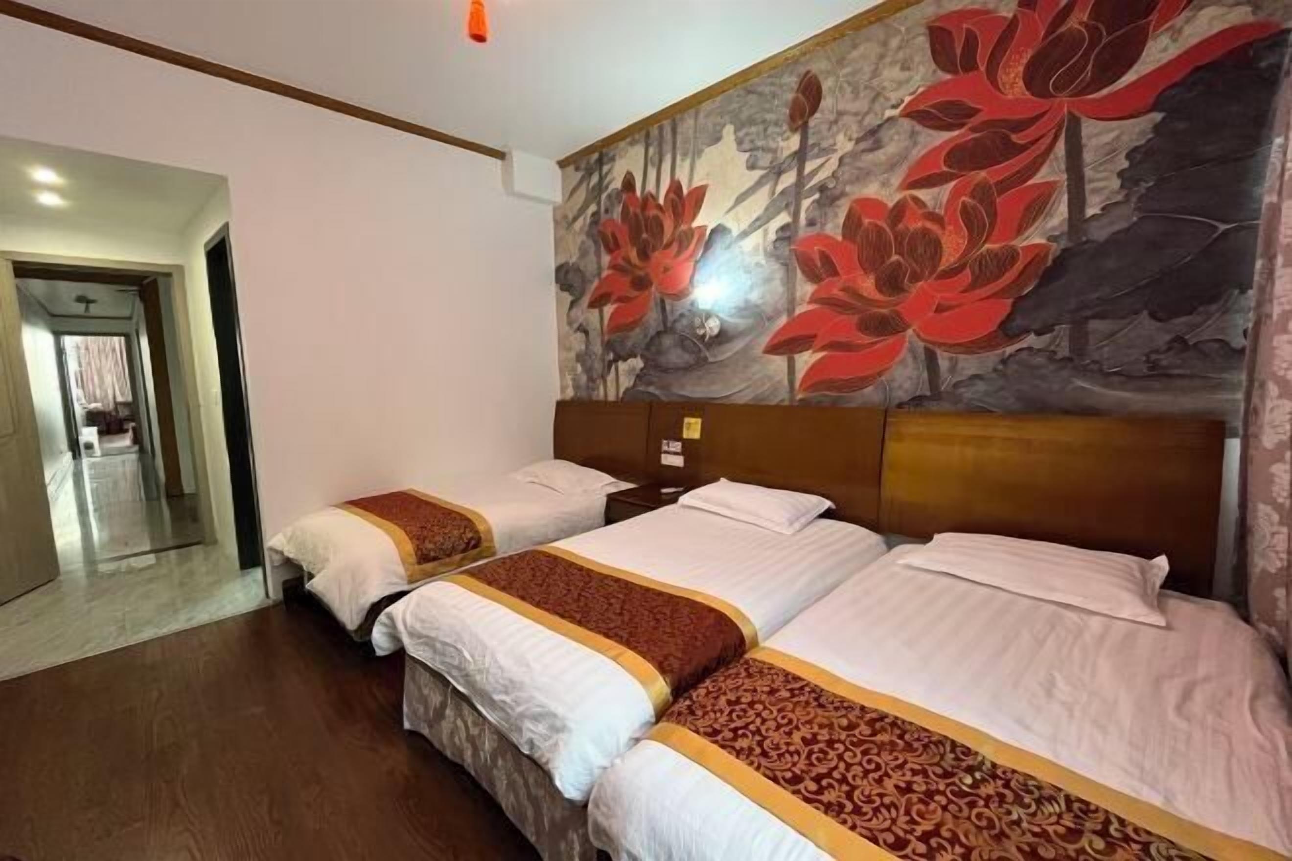 A hotel room with two beds, a large floral mural on the wall, and a wooden floor.