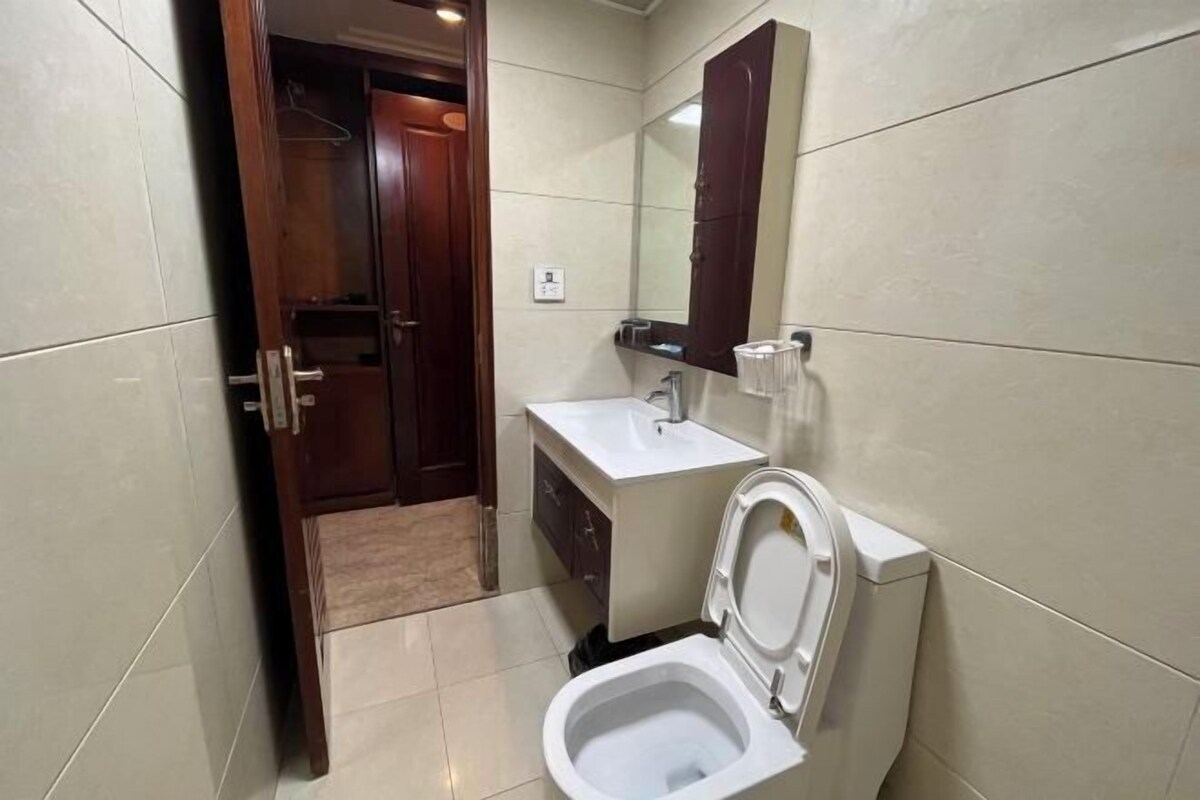 A compact bathroom with a toilet, sink, and mirror.