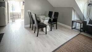 A modern loft with a glass dining table, dark chairs, and a high ceiling with a skylight. - Unique Modern Luxury 2 Bedroom Apartment (Chapleau)