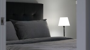Een slaapkamer met een bed, een nachtkastje en een lamp.