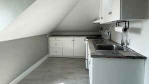 A modern kitchen with white cabinets, a dark countertop, and a visible sink. - Unique Modern Luxury 2 Bedroom Apartment (Chapleau)