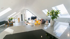 A modern kitchen with a large island, skylights, and a dining area with a view.