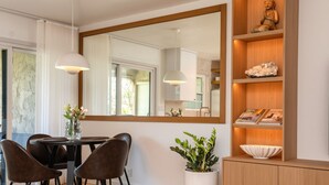 A dining area with a table, chairs, a large mirror, a potted plant, and a wooden shelf with decorative items. - Beautifully designed with Mountain View, Resort Amenities, Golf, Office + More (Palm Springs)