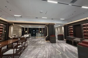 A spacious hotel lobby with a marble floor, seating areas, and a central column.