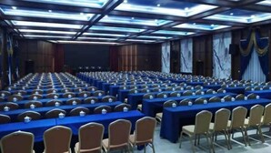 A conference room with rows of tables and chairs, equipped with nameplates and microphones. - Long Cheng Hotel (Xiangxiang)