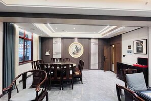 A conference room with a round table, chairs, and a large wall clock. - Long Cheng Hotel (Xiangxiang)