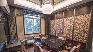 A conference room with a glass table surrounded by wooden chairs, a small side table, and a decorative wall panel. - Long Cheng Hotel (Xiangxiang)