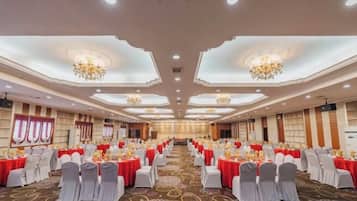 A banquet hall with rows of tables, chairs, and chandeliers.