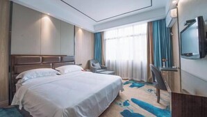 A hotel room with a bed, a TV, a desk, and a window with curtains. - Long Cheng Hotel (Xiangxiang)