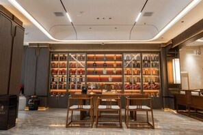 A modern interior with a central dining area, a wall of neatly arranged bottles, and a clean, minimalist design. - Long Cheng Hotel (Xiangxiang)