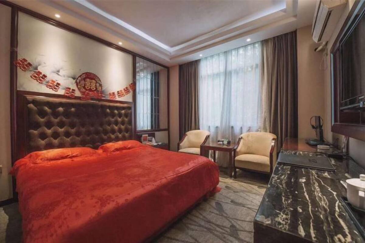 Quarto de hotel com uma cama grande, escrivaninha, cadeira e televisão.