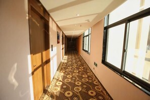 A hotel corridor with patterned carpet, doors, and windows. - Donghu Hotel (Shouning)