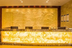A reception desk with a marble counter and a wall mural. - Donghu Hotel (Shouning)