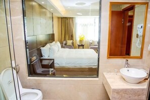 A hotel room with a glass-enclosed bed, a bathroom with a sink and mirror, and a view of the hotel lobby. - Donghu Hotel (Shouning)