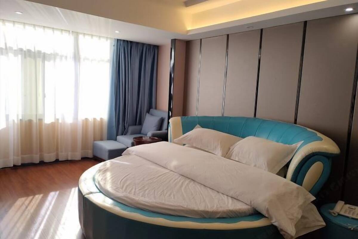 A modern hotel room with a large bed, a seating area, and a view of the outdoors.
